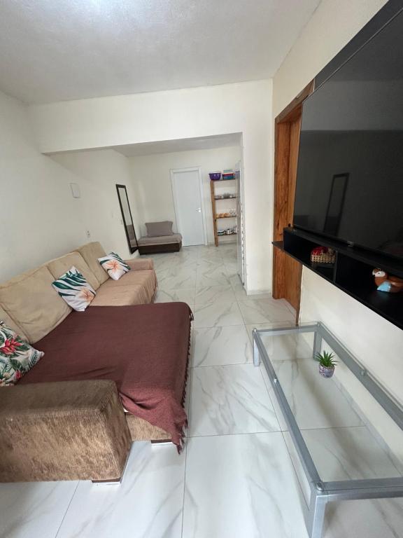 een woonkamer met een bank en een flatscreen-tv bij Casa in Bombinhas