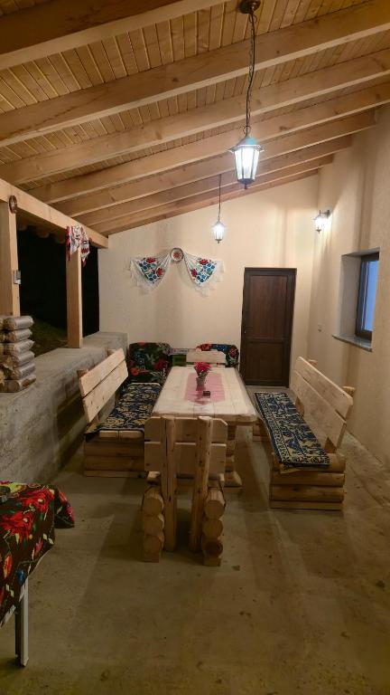 a room with a table and benches in a room at La Murmur de Padure in Bălnaca