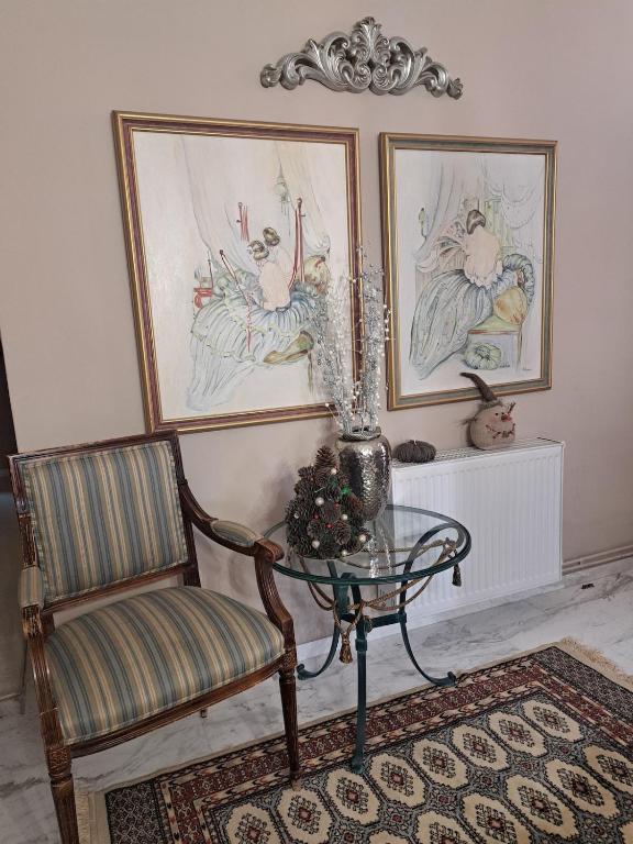 een kamer met een glazen tafel en een stoel en schilderijen bij Karachalios Maisonette in Karyes