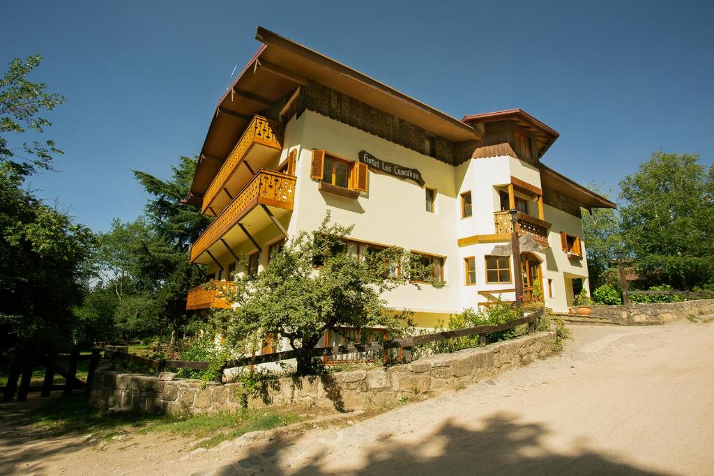 a large building on a stone wall with a tree at Hotel Las Cascadas in La Cumbrecita