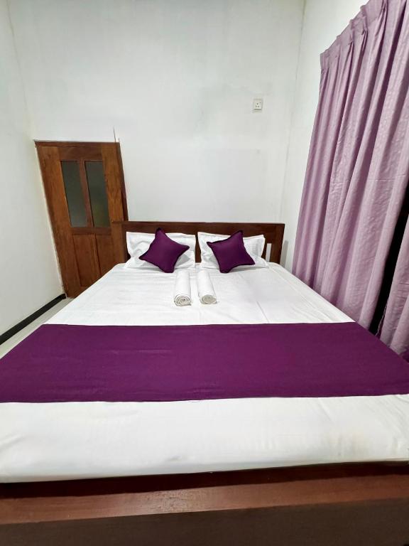 a bedroom with a large bed with purple pillows at Villa Nevya in Weligama