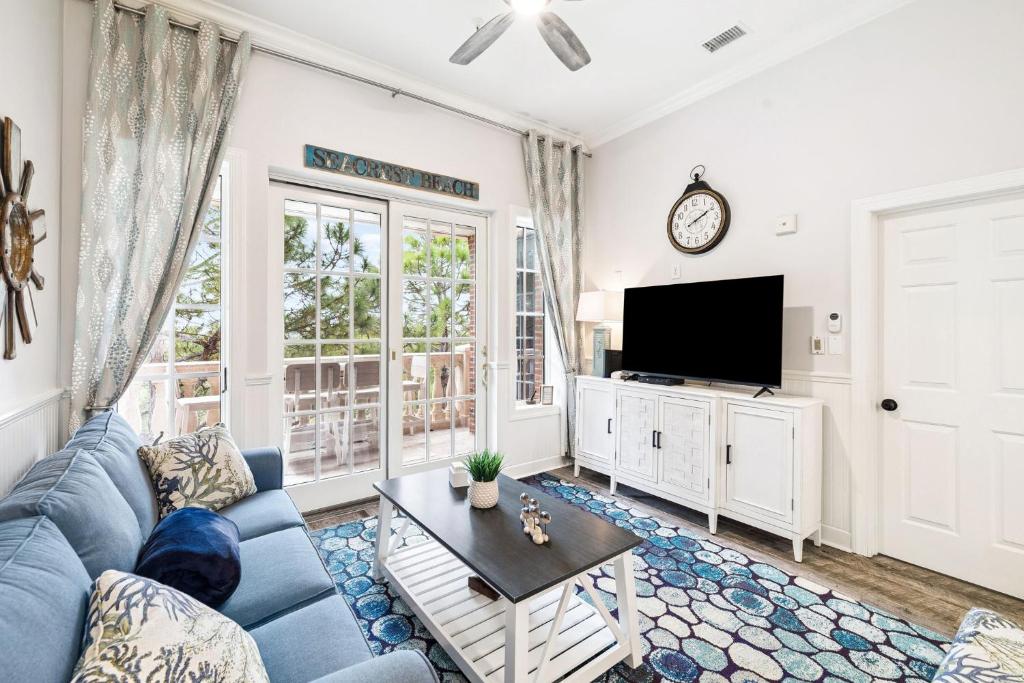 a living room with a blue couch and a tv at The Magnolia by 30A Escapes in Rosemary Beach