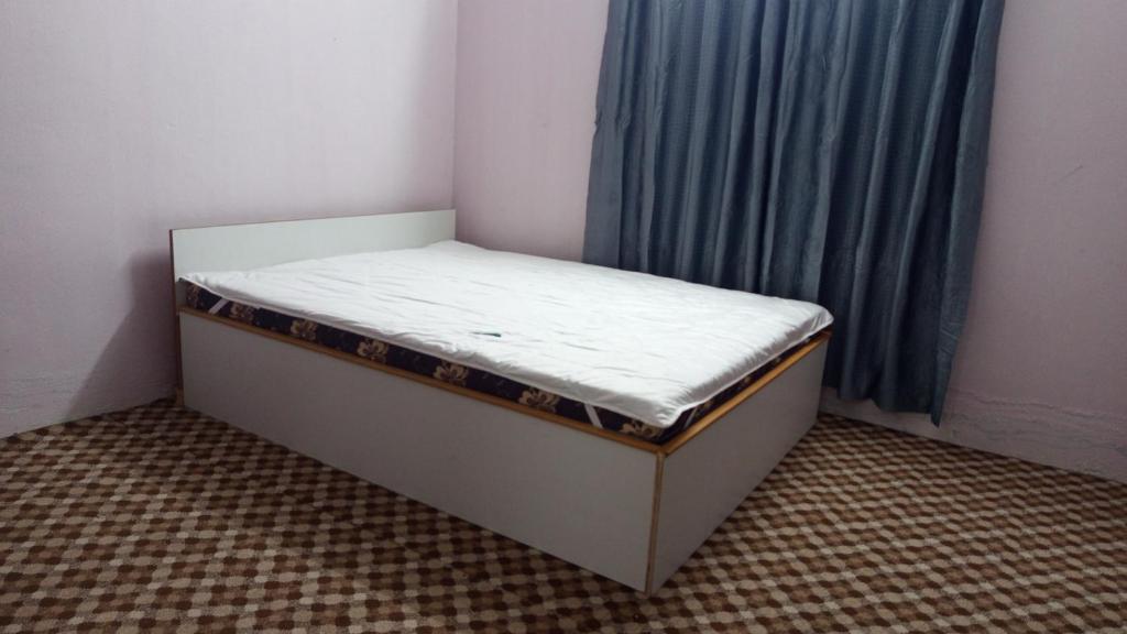 PokharaAnnapurna Himdrishya Pokhara的一张蓝色窗帘的房间的小床