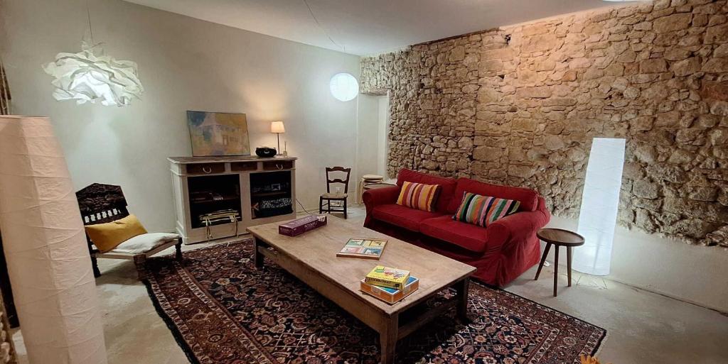 a living room with a red couch and a stone wall at Maison boutet 9 in Fanjeaux