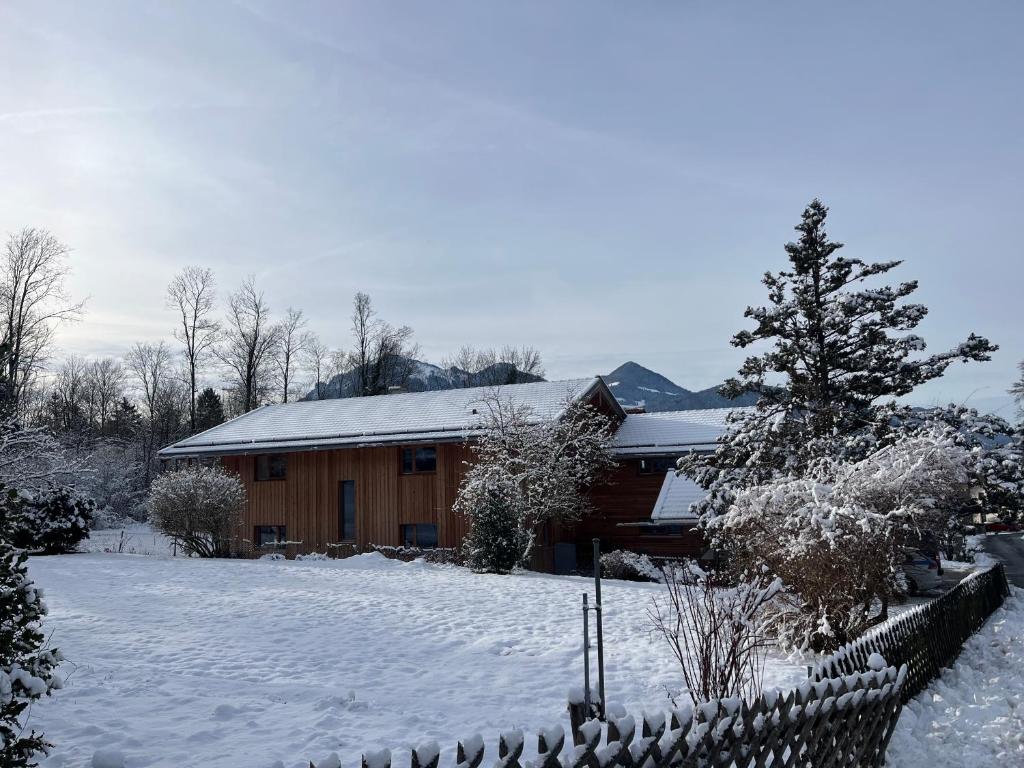 una casa coperta di neve di fronte a una recinzione di Ferienwohnung Waldzeit a Staudach-Egerndach