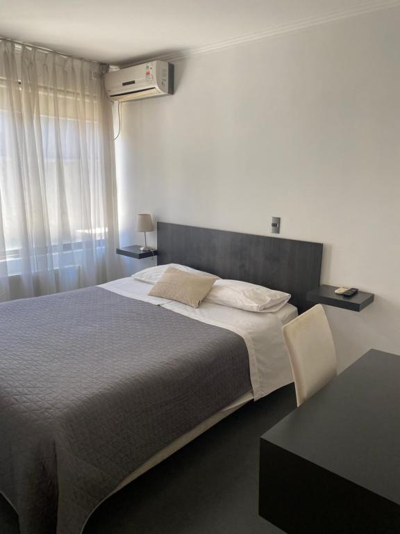 een slaapkamer met een groot bed en een tafel bij Hotel Stella in Talca