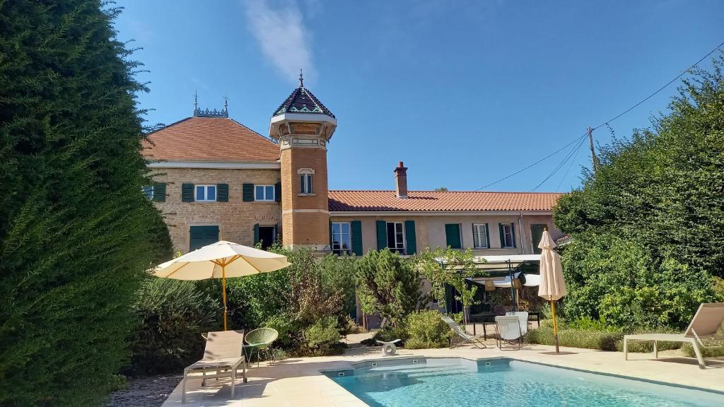 a house with a swimming pool and a building with a clock tower at La Tour Bleue in Chânes