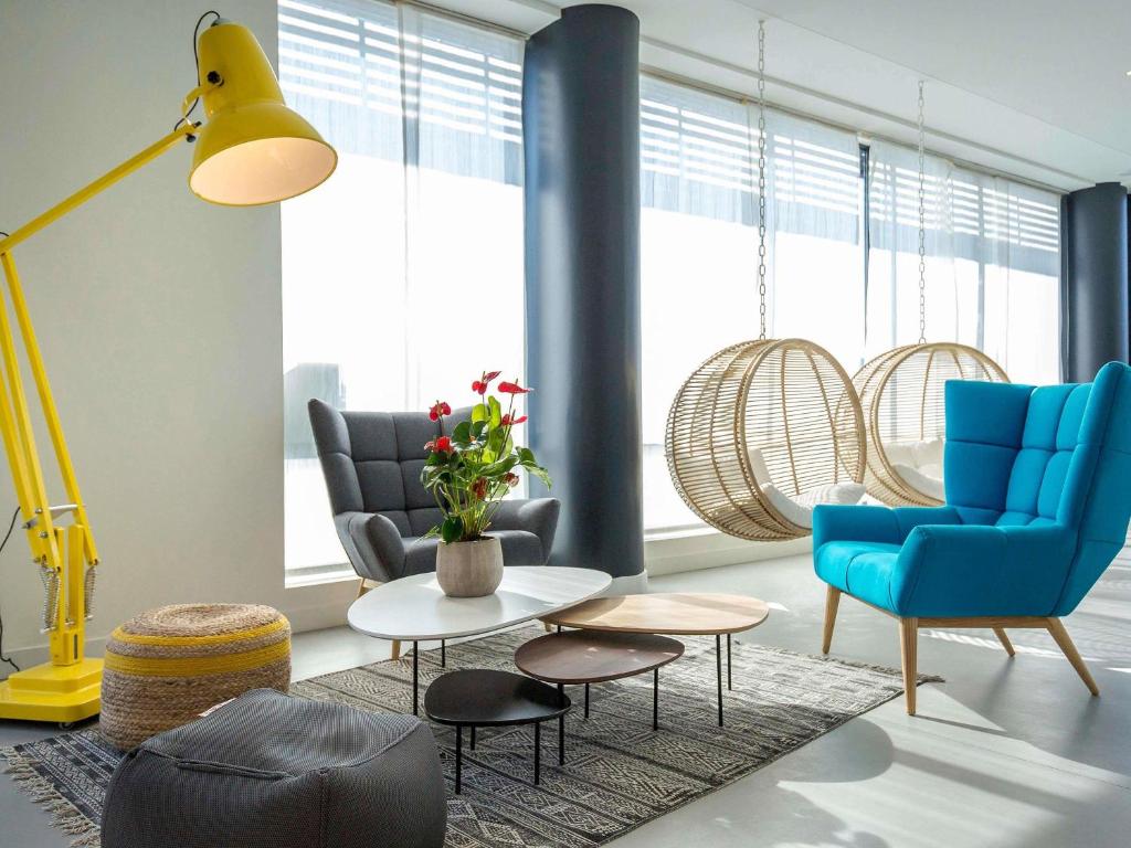 un salon avec des chaises bleues et une table dans l'établissement ibis Lyon Sud Vienne Saint-Louis, à Vienne