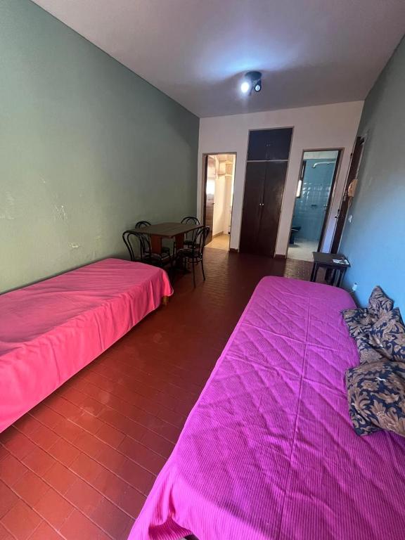two beds in a room with a table and pink sheets at Miramar 19 in Miramar