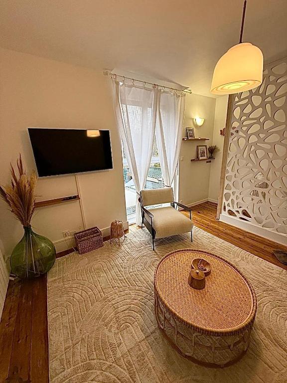 a living room with a tv and a couch and a table at Appartement cocooning proche de lille in Loos