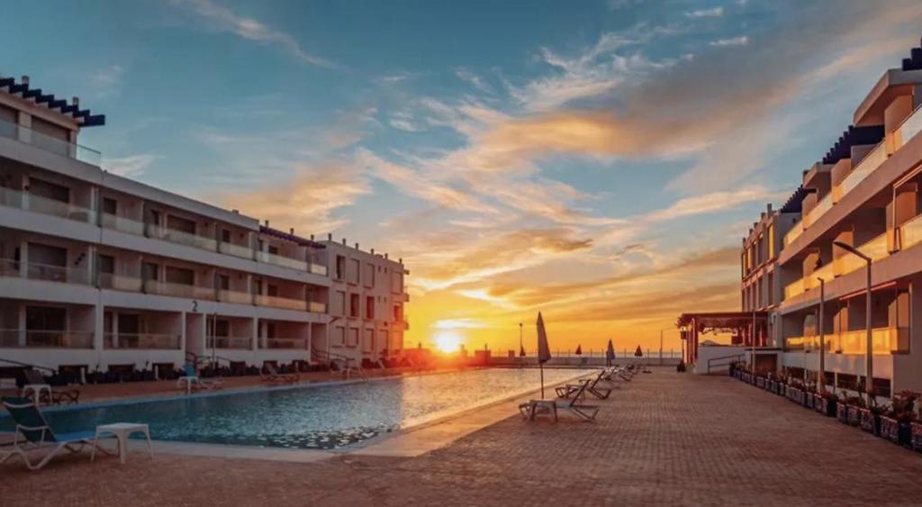 a hotel with a pool in front of a sunset at Sea & Pool View Apt 1 in Aourir