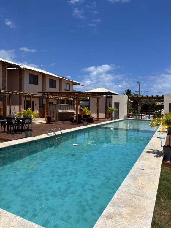 a swimming pool with blue water in front of a building at 2 QUARTOS, Condomínio Villa de Rodes IMBASSAÍ Super bem localizado, Próximo a PRAIA, FARMÁCIAS, MERCADO E RESTAURANTES in Imbassai
