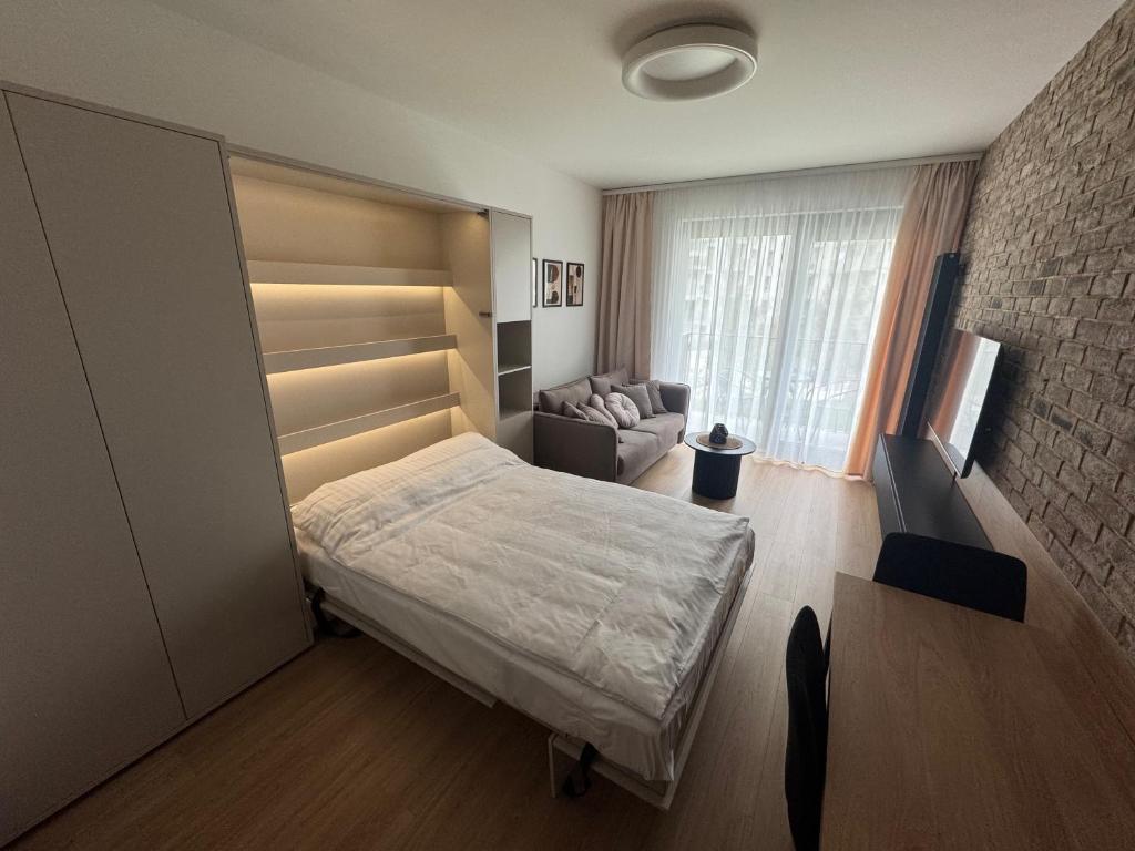 een kleine slaapkamer met een bed en een bank bij Żurawie II Popiełuszki 2A 51 in Gdańsk