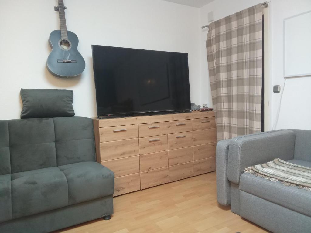 een woonkamer met een flatscreen-tv en een gitaar bij Komplette Wohnung Schwarzwaldpforte Casa BaLi direkte Buchung möglich keine Freigabe mehr erforderlich in Bad Liebenzell