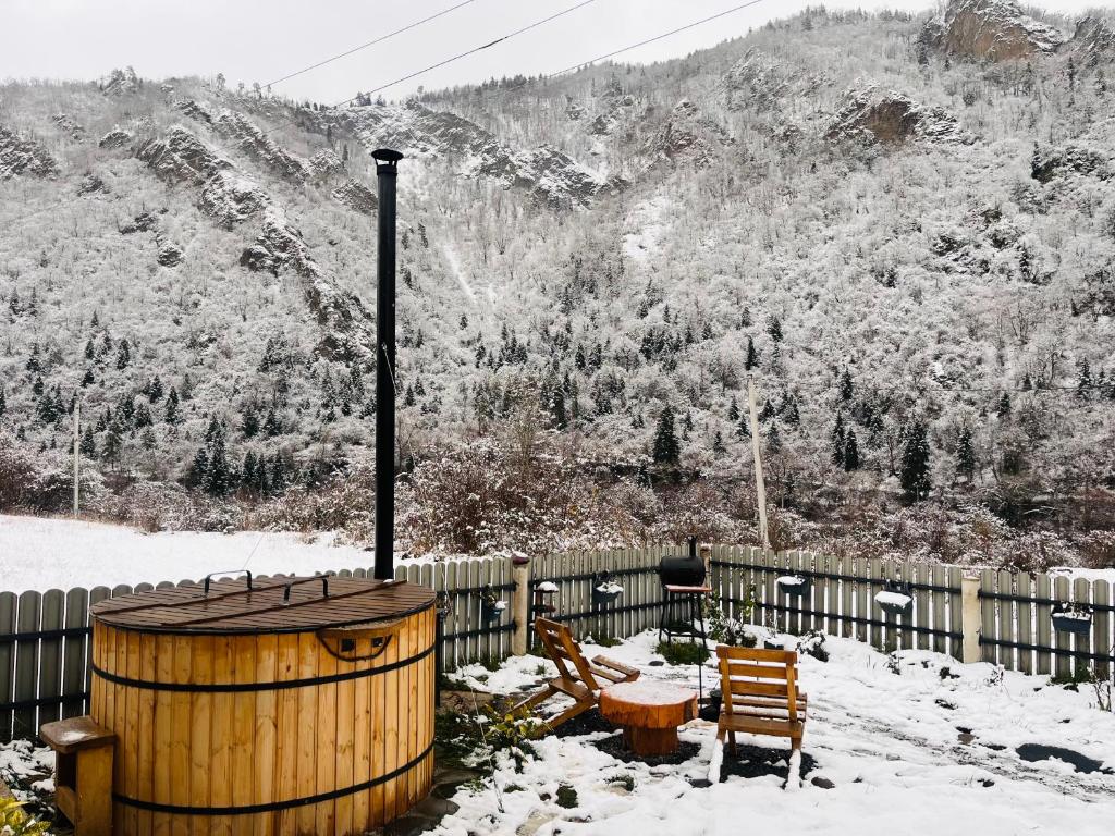 een houten vat, een tafel en stoelen in de sneeuw bij Woodlandia Resort Borjomi in Borjomi
