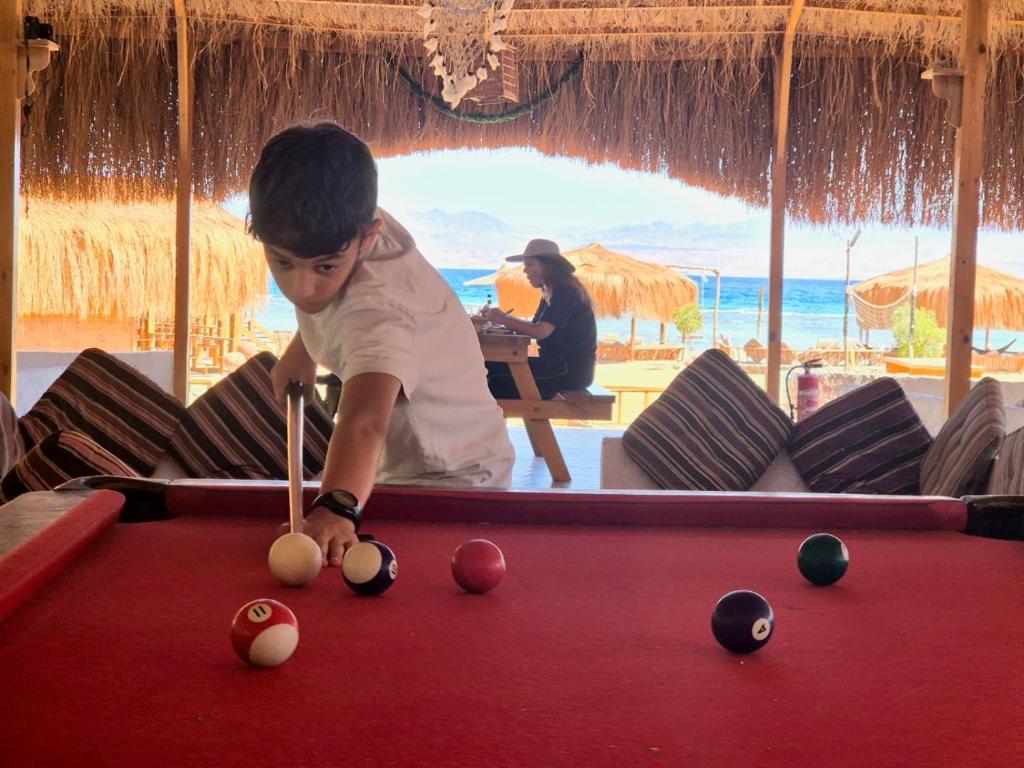 a young boy playing pool on a pool table at Relax Beach Camp in Nuweiba‘ el Muzeinah