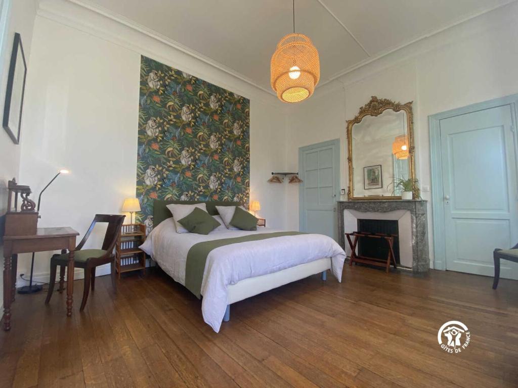 een slaapkamer met een bed, een open haard en een spiegel bij La maison bachelet in Claira