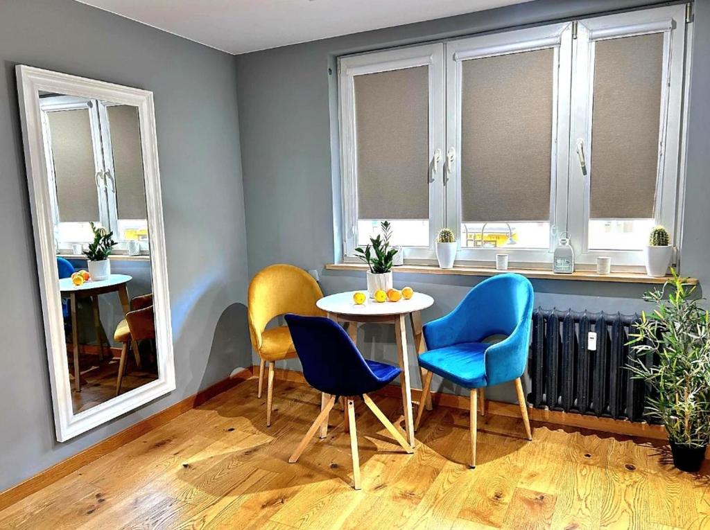 a room with a table and chairs and windows at Apartament Pastelowy Tukan in Kwidzyn