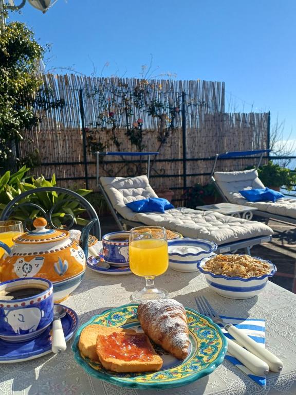 une table avec une assiette de nourriture et un verre de jus d'orange dans l'établissement Casa del Corriere, à Positano