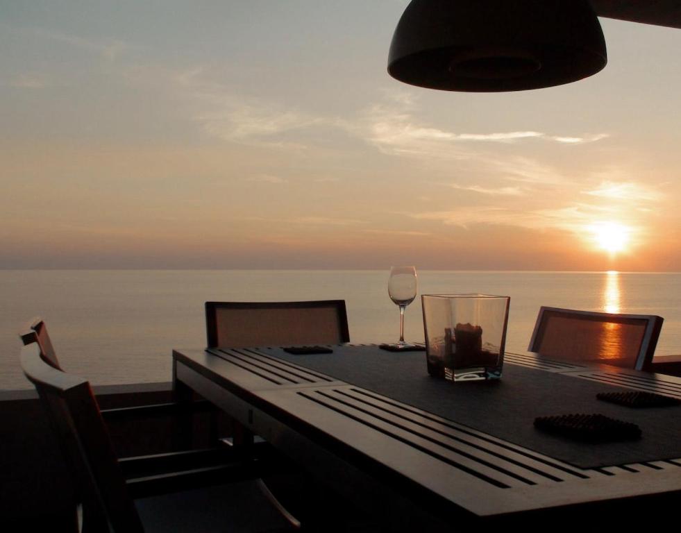 a table with a glass of wine on a balcony at Sea Horizon Private Villa with Panoramic Sea Views in Nea Skioni