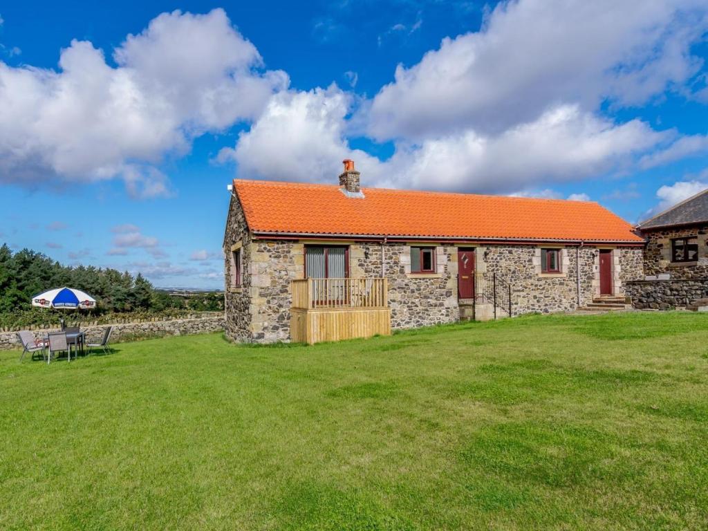 a stone cottage with an orange roof on a grass field at 3 Bed in Belford oc-79178 in Belford