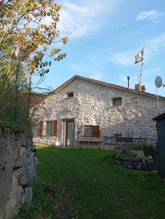 a stone house with a grass yard in front of it at Casa Umberna in Asiago