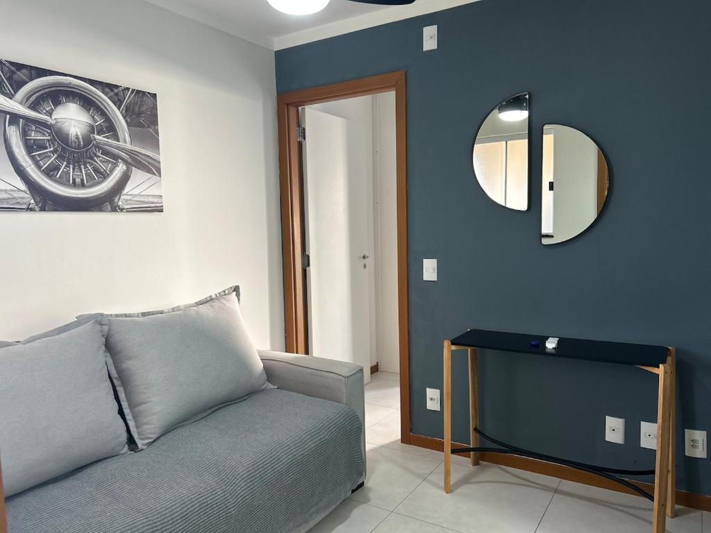een woonkamer met een bank en een spiegel bij Espaço completo Bauru in Bauru