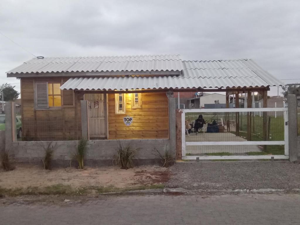 una piccola casa di legno con un portico e un cancello di Morada do Verão a Imbé