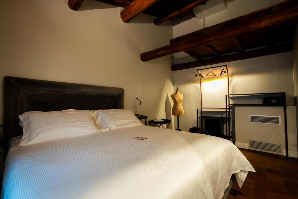 une chambre avec un grand lit avec des draps blancs dans l'établissement Locanda Sibilla Luxury Suites, à Tivoli