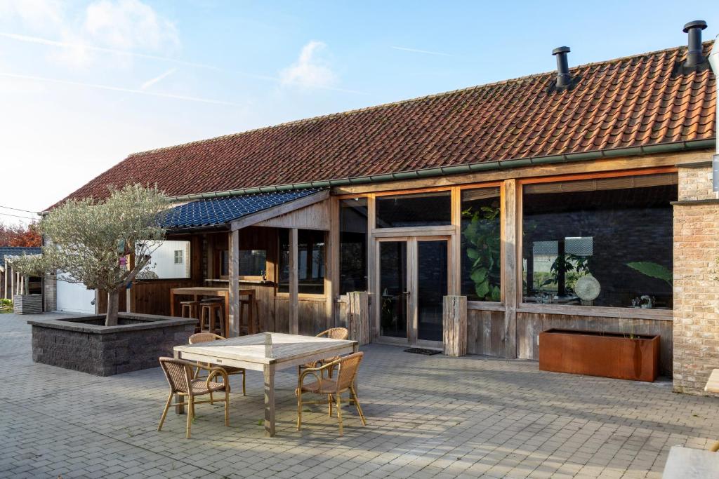 een terras met een tafel en stoelen voor een gebouw bij B&B De Leestjespolder in Moerkerke