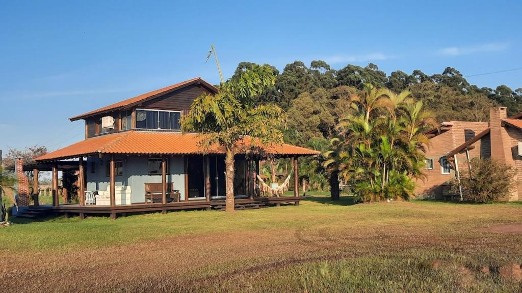 una casa con una palma di fronte di Cabana Raio de Sol RS a Osório