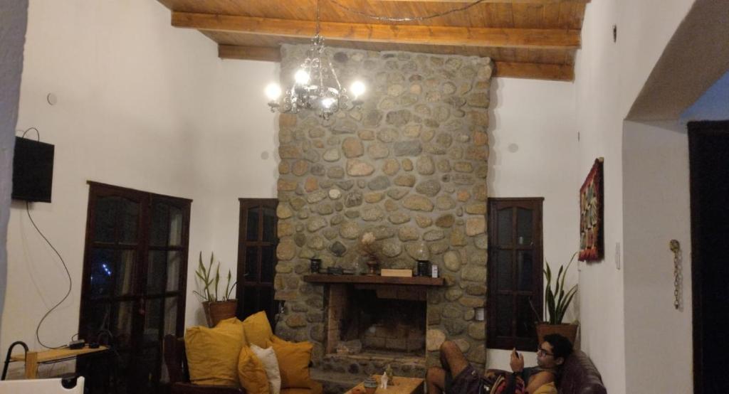 een woonkamer met een stenen open haard en een bank bij La Apacheta in Tafí del Valle