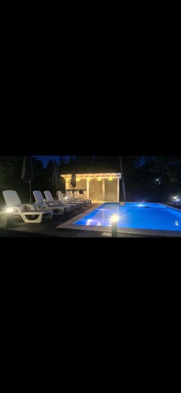 una vista di una piscina di notte con sedie di La Casa Bianca a Avrig