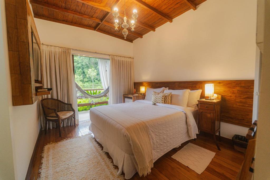 a bedroom with a large bed and a window at Pousada Tucano Do Cuiabá in Itaipava