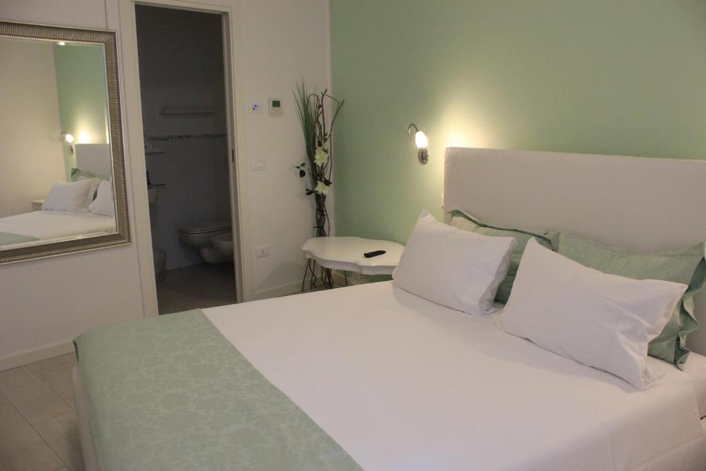 a bedroom with a bed with white pillows and a mirror at Punto 41 in Peschiera del Garda