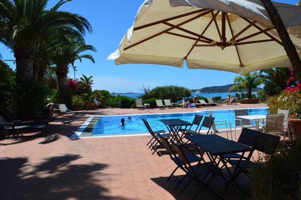 a pool with tables and chairs and an umbrella at Residence Fenicia in Villasimius