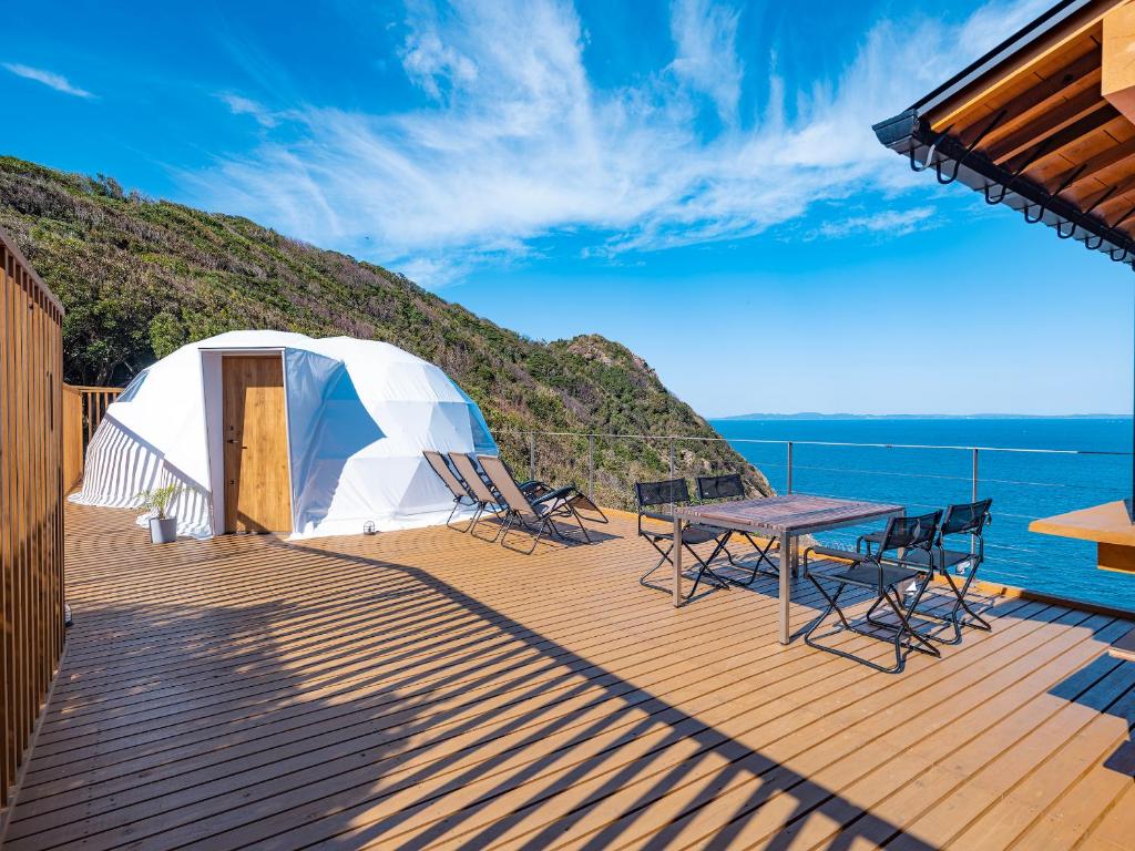 a deck with a tent and a table and chairs at On The Cliff in Karatsu