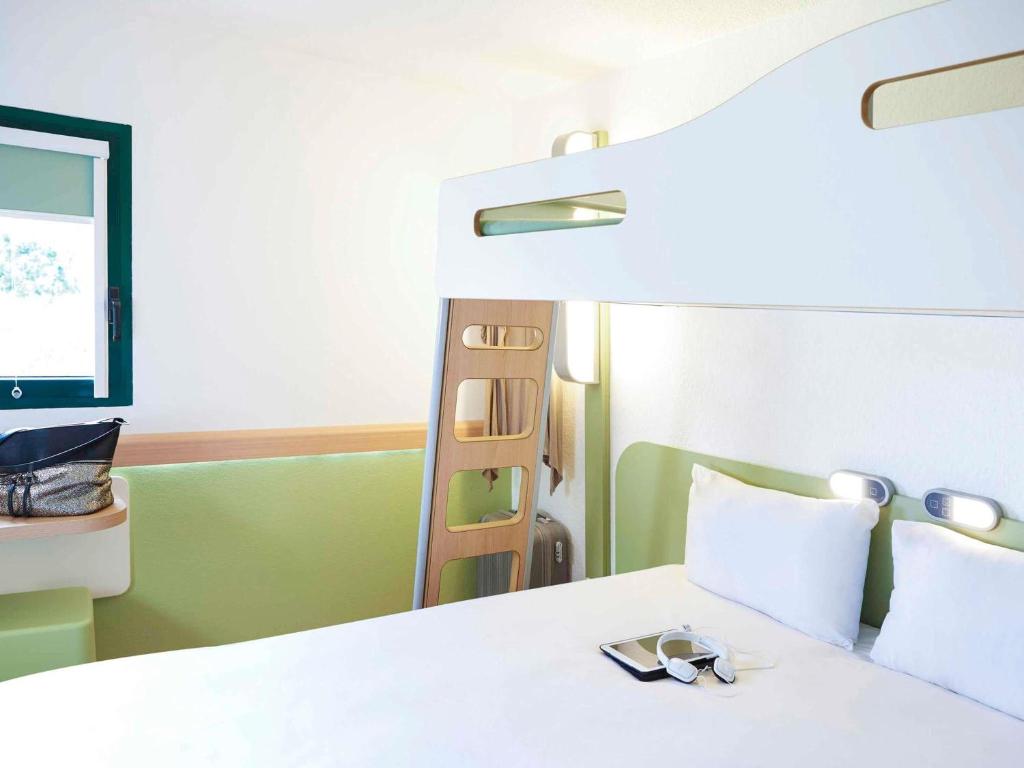 een slaapkamer met een wit bed en een spiegel bij ibis budget Albi Terssac in Terssac