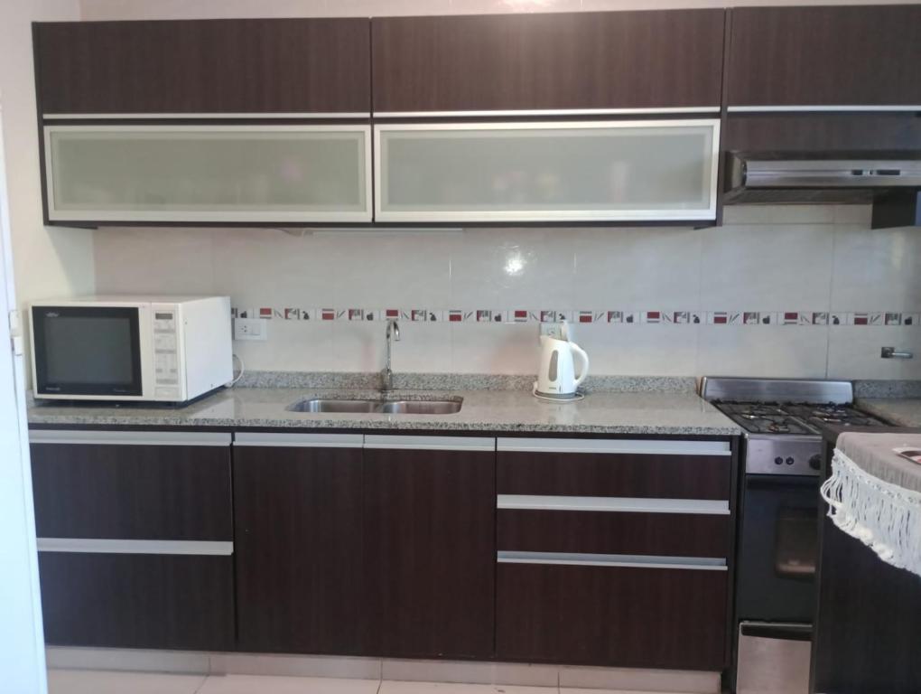 a kitchen with brown cabinets and a microwave and a sink at San Juan Santo Tome in Santo Tomé