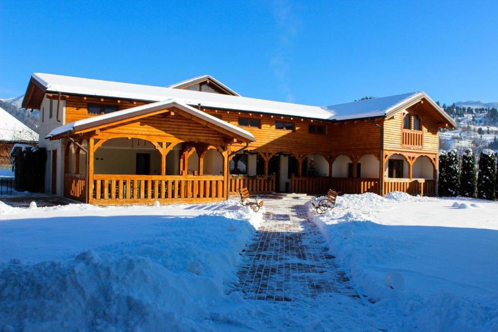 a log cabin with snow in front of it at CABANA ZIMBRU in Băile Borşa