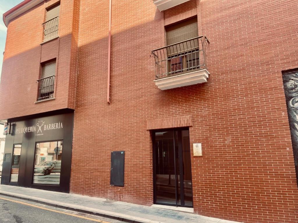 een gebouw van rode baksteen met een deur en een balkon bij Apartamentos Palma del Río CAROLA in Linares