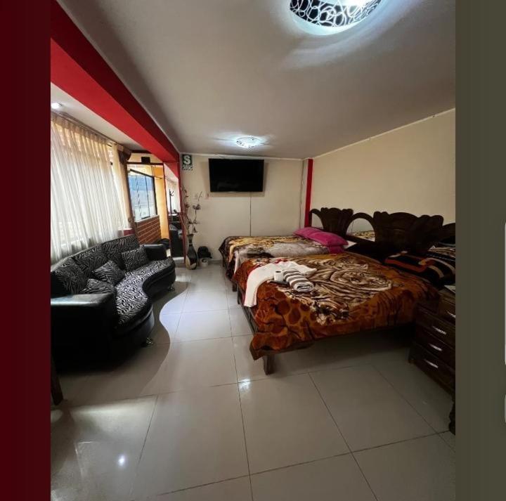 a bedroom with two beds and a couch and a tv at Hospedaje secretos in Huancayo