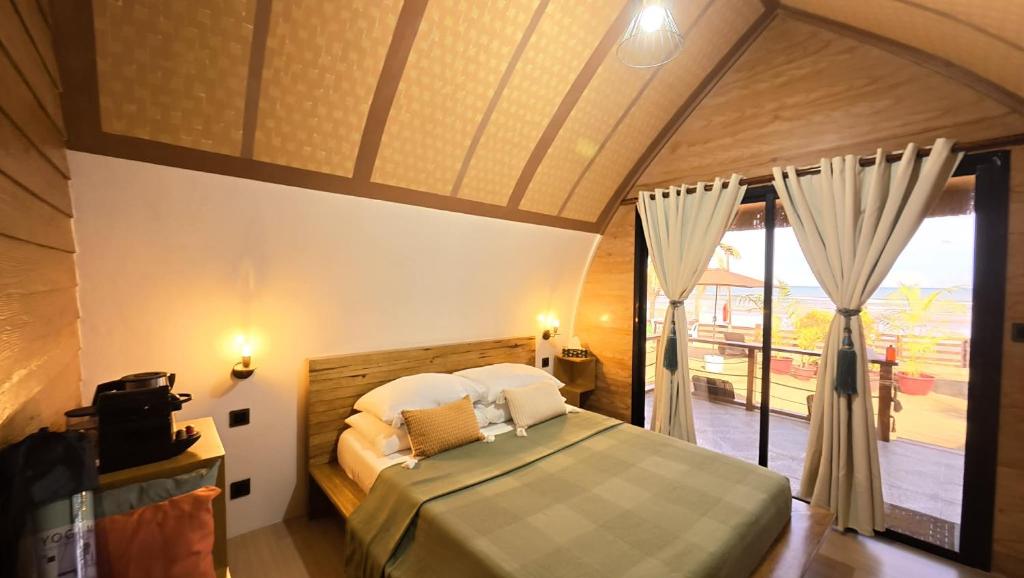 a bedroom with a bed and a large window at Kubotique Beachfront Staycation in El Nido