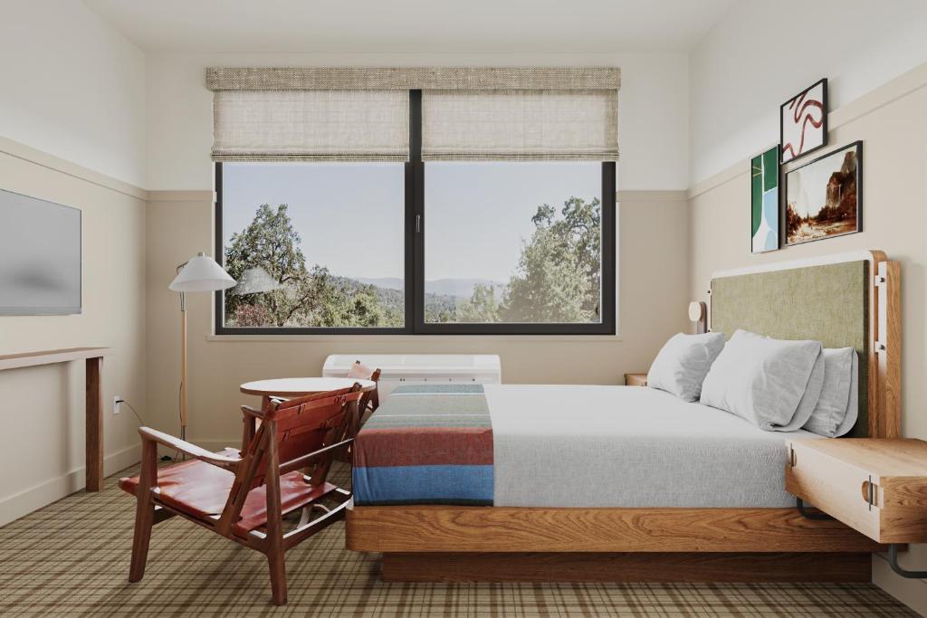 a bedroom with a bed and a chair and a window at Outbound Yosemite in Oakhurst