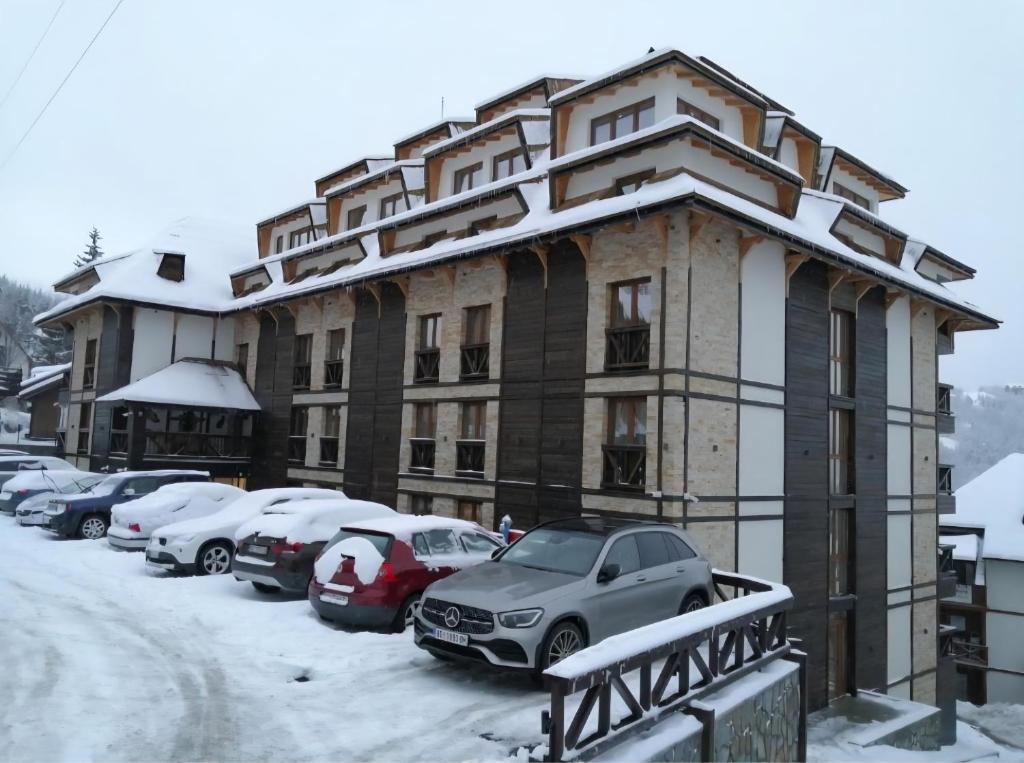 een gebouw met auto's geparkeerd op een met sneeuw overdekte parkeerplaats bij Mountain Lux Zoned in Kopaonik