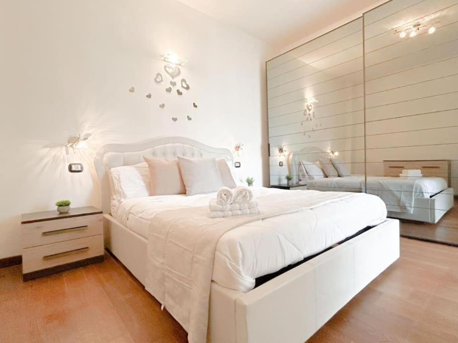 a white bedroom with a large bed and a mirror at Elegante appartamento - Aeroporto - Porto - WiFi - Casa Gelsomino in Genoa