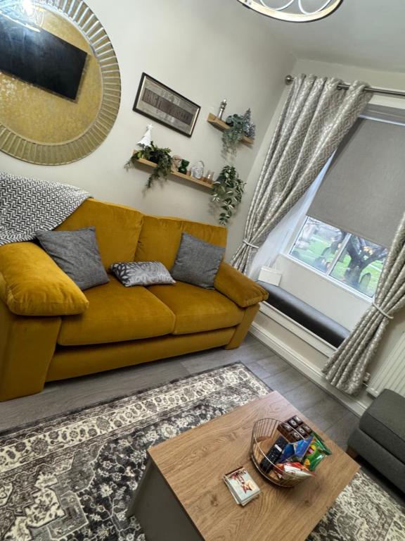 a living room with a yellow couch and a table at Church view in Conisbrough