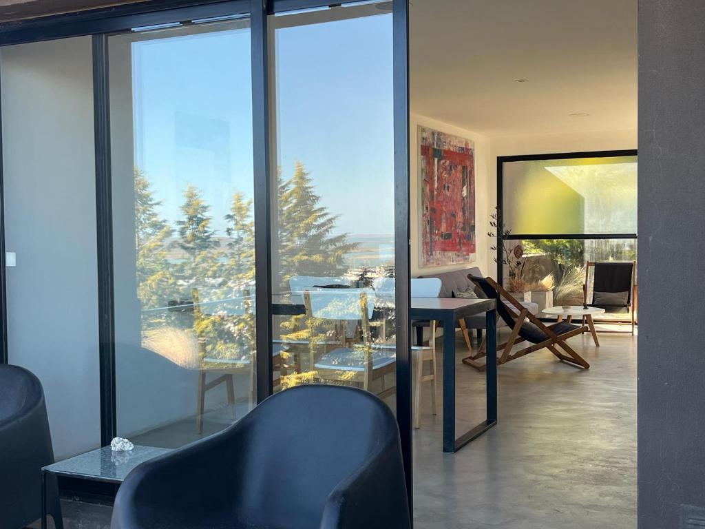 een woonkamer met glazen ramen en een tafel en stoelen bij HOMU DEP - Vista al mar in Puerto Deseado