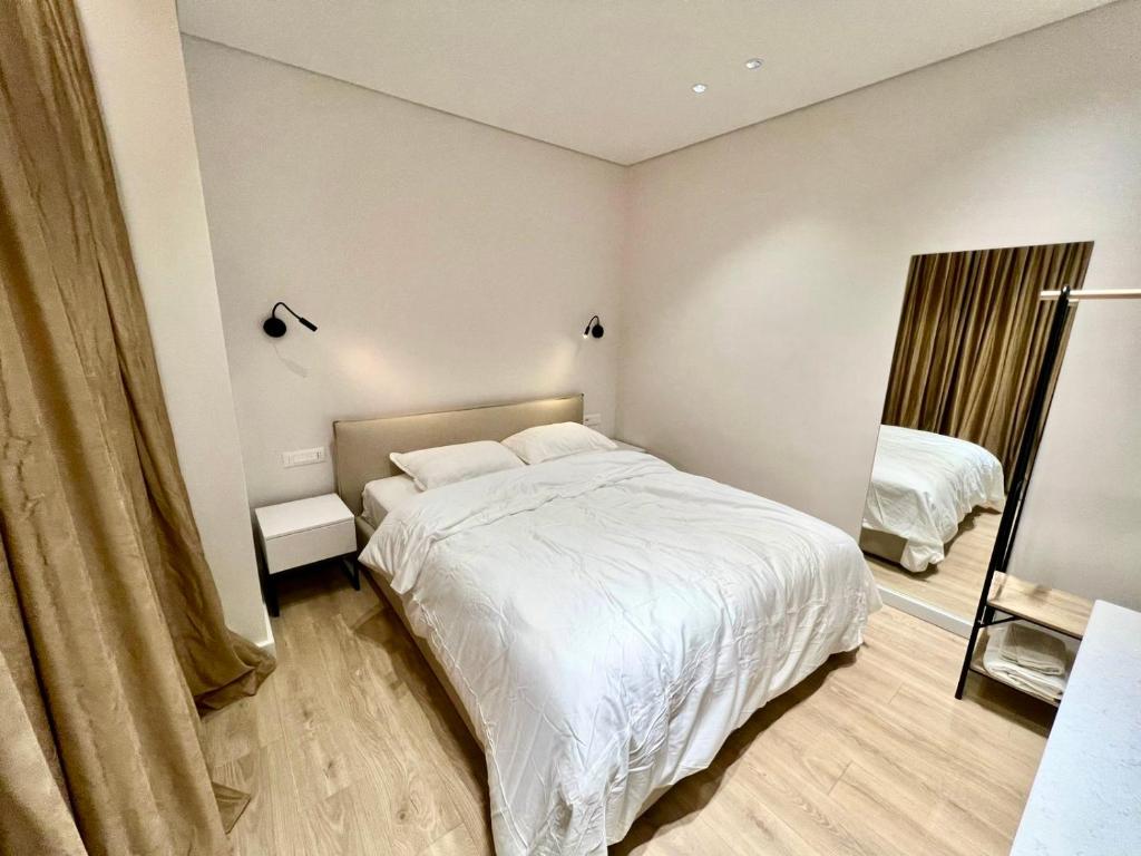 une chambre avec un lit blanc et un miroir dans l'établissement Tirana Square Apartments, à Tirana