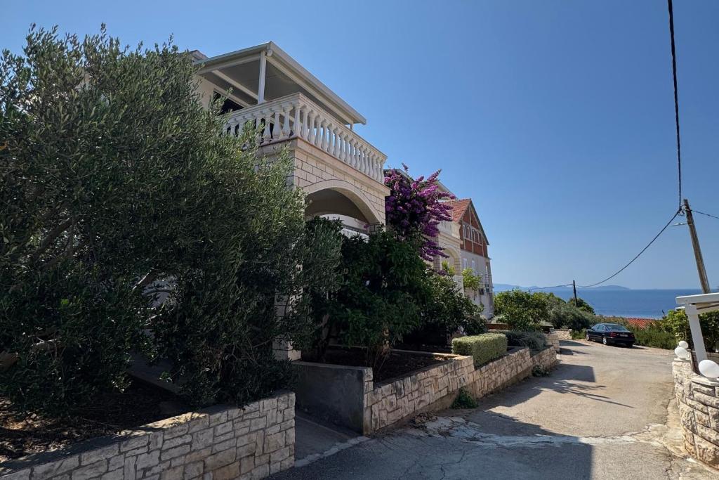 a brick house with bushes and flowers on a street at Apartments by the sea Prizba, Korcula - 149 in Prizba